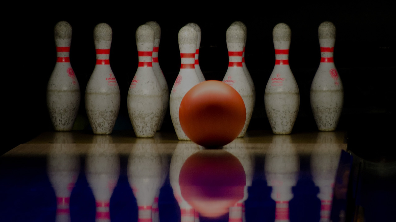 bowling ball rolling down a lane to pins